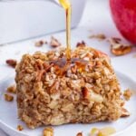 Maple syrup is poured over a serving of baked apple oatmeal.