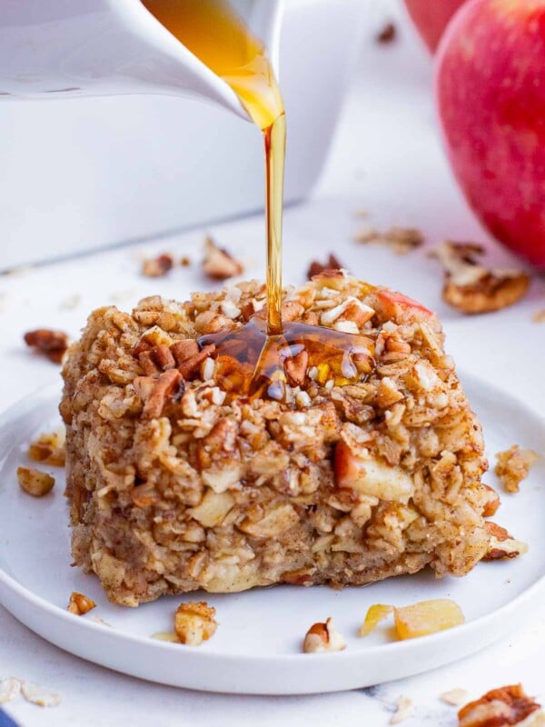 Maple syrup is poured over a serving of baked apple oatmeal.