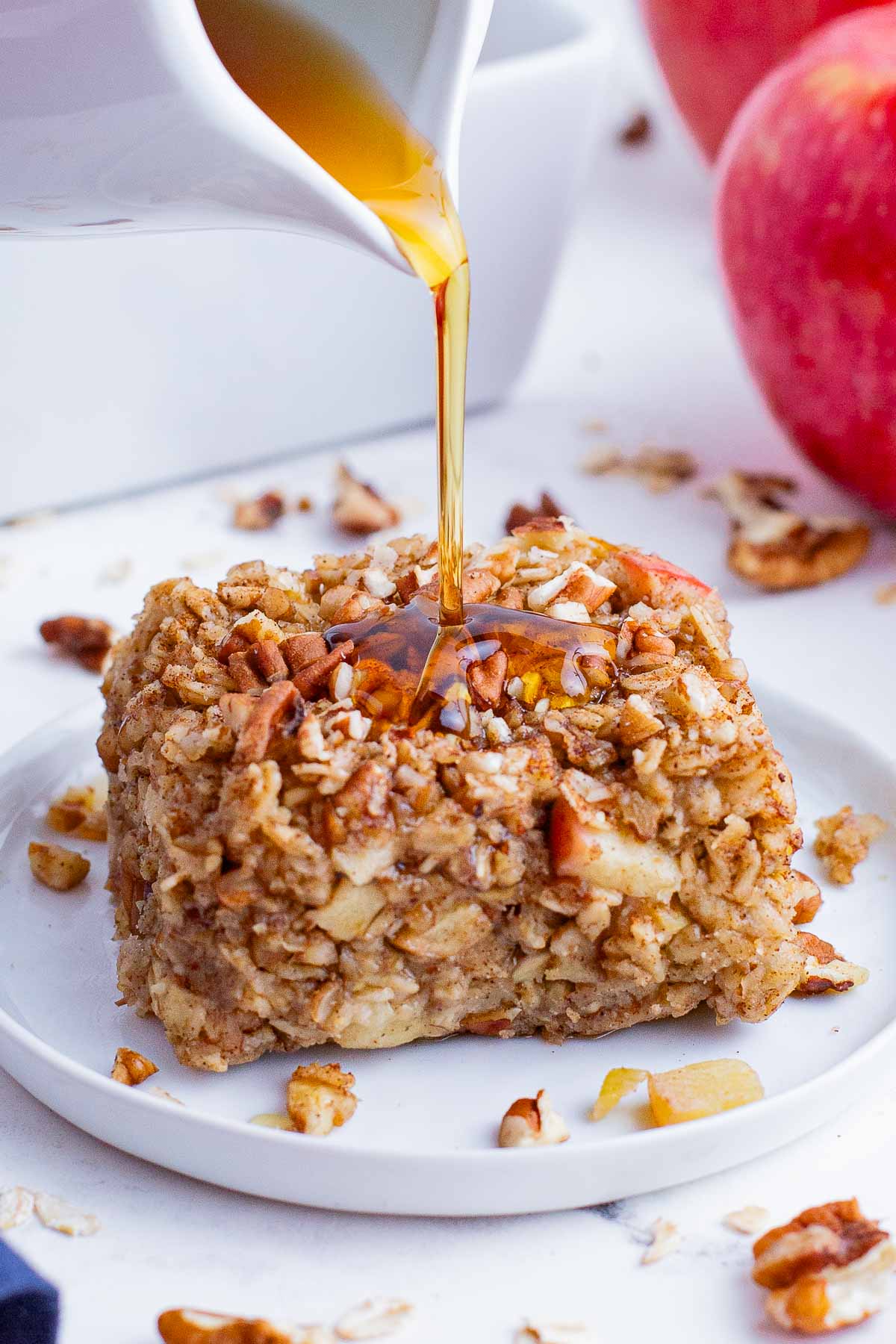Maple syrup is poured over a serving of baked apple oatmeal.