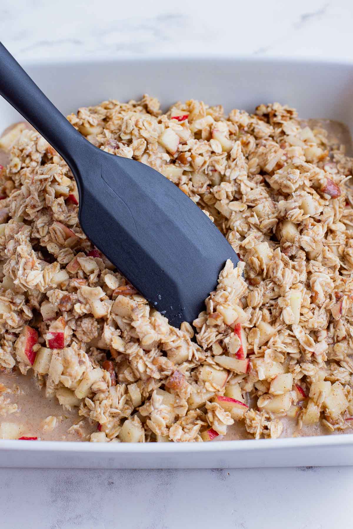 Apples are stirred into the oatmeal mixture.