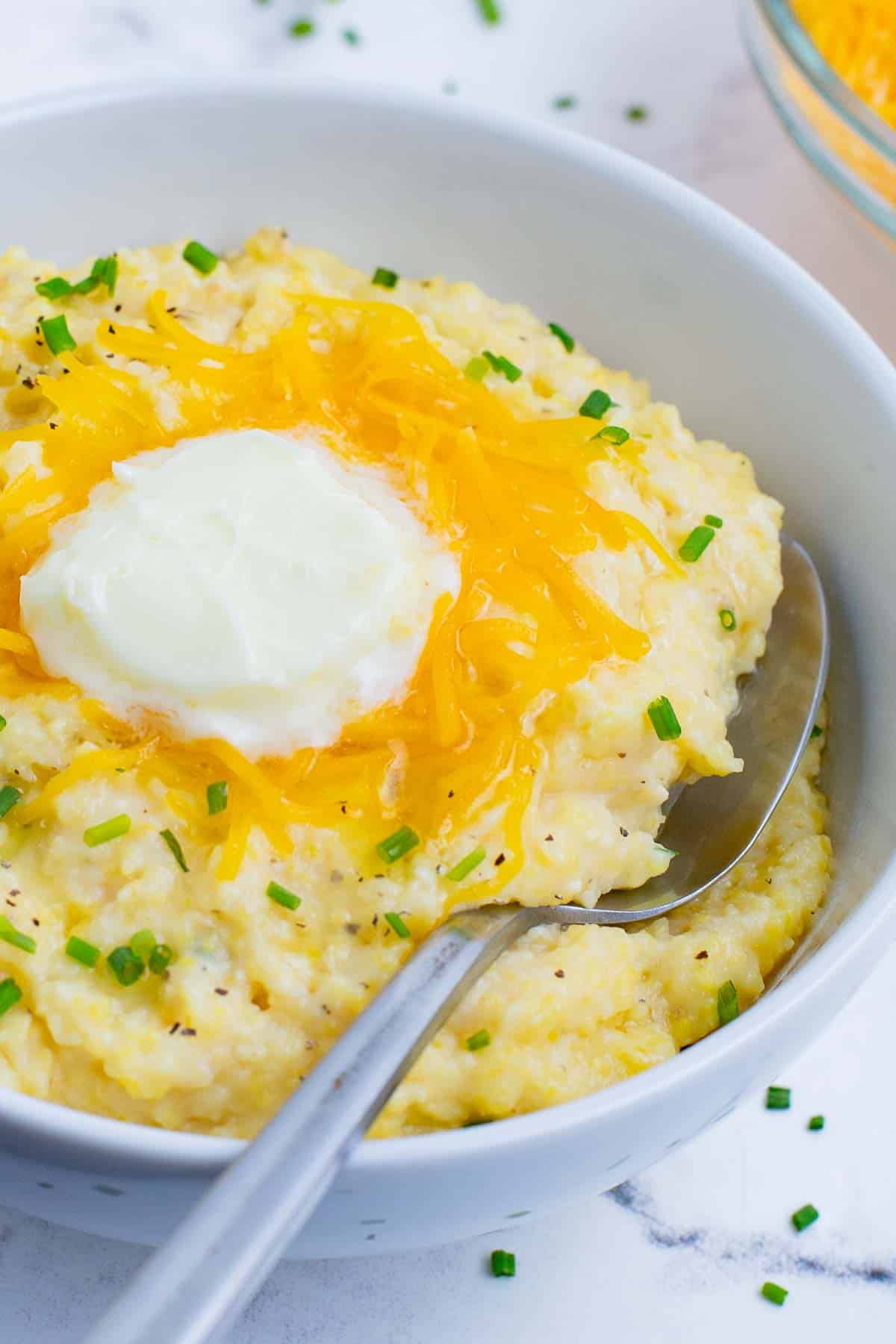A spoon scoops out a serving of cheese grits.