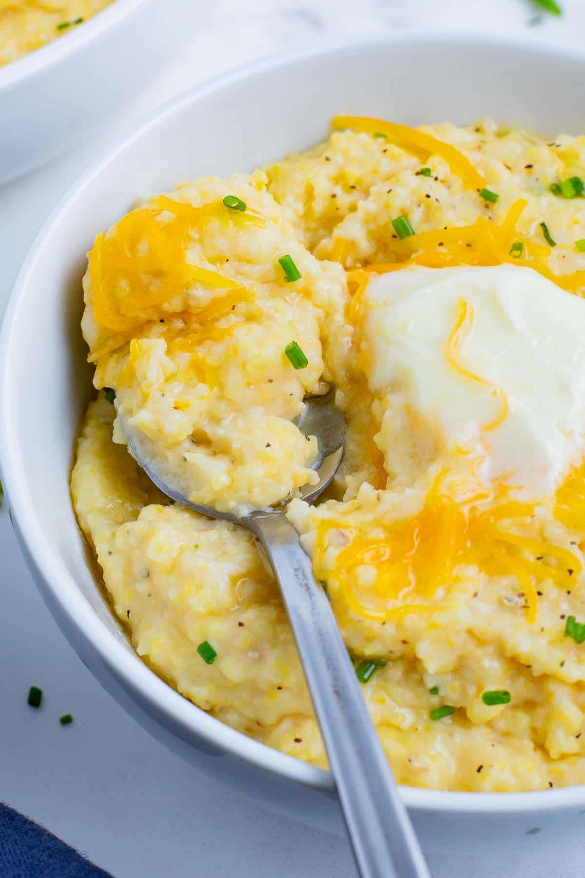 Cheesy grits in a white bowl with a spoon.