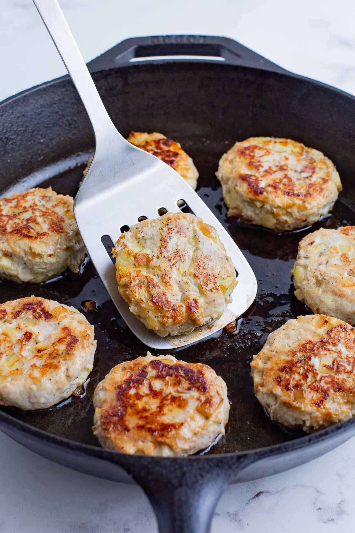 A spatula flips the sausage patties during cooking.