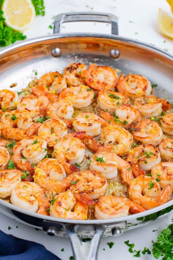 Shrimp is cooked in a skillet in a butter garlic sauce with fresh lemon.