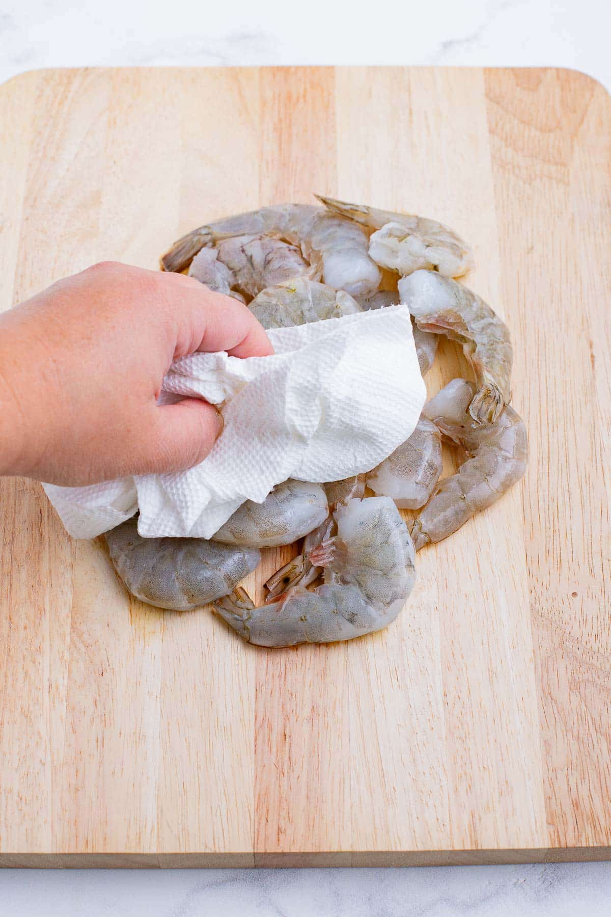 A hand pats the shrimp dry.