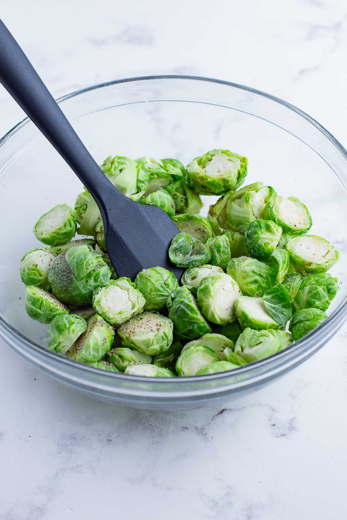 Brussels sprouts are seasoned before baking.