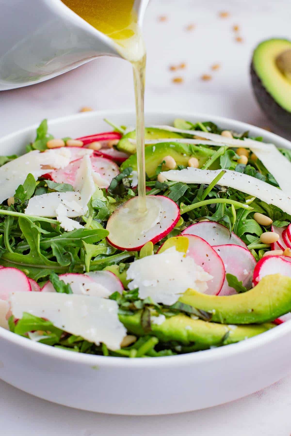 Dressing is poured over the simple arugula salad.