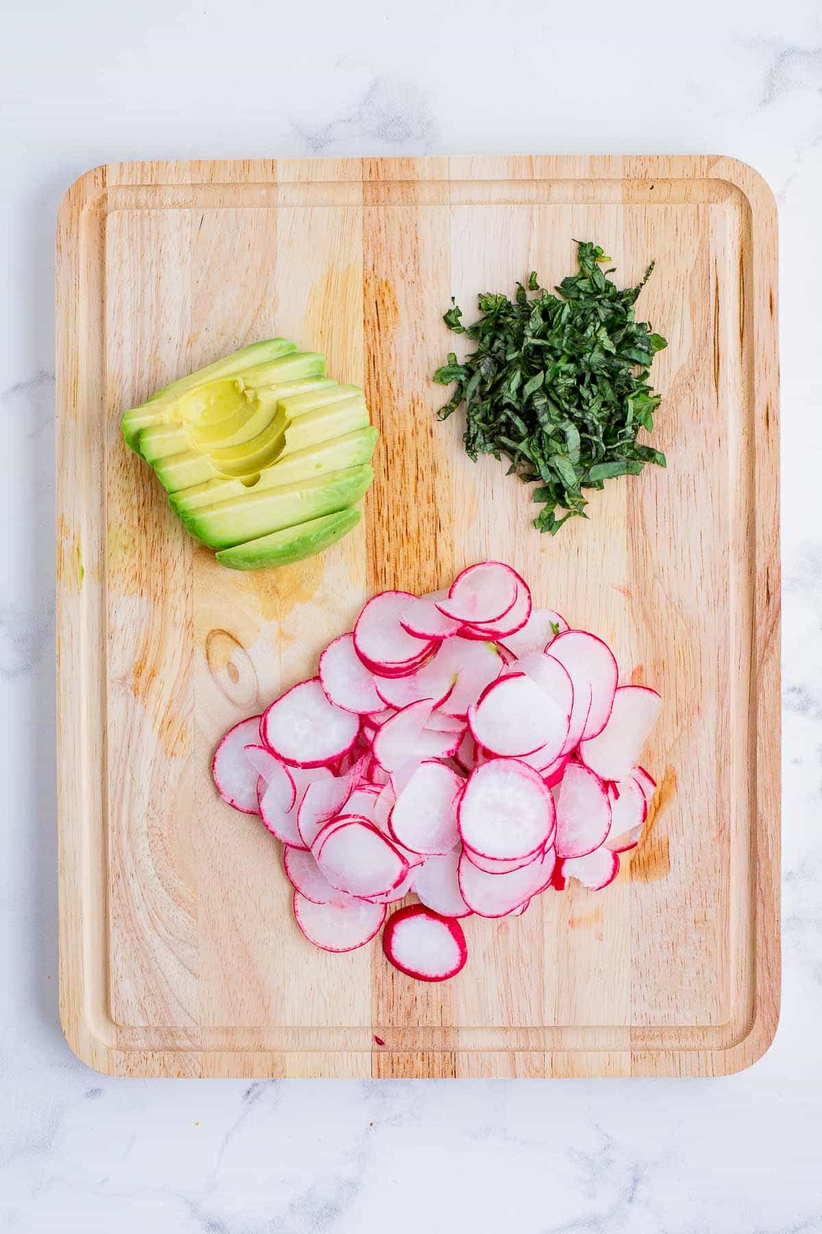 Radishes, avocado, and basil are cut for the salad.
