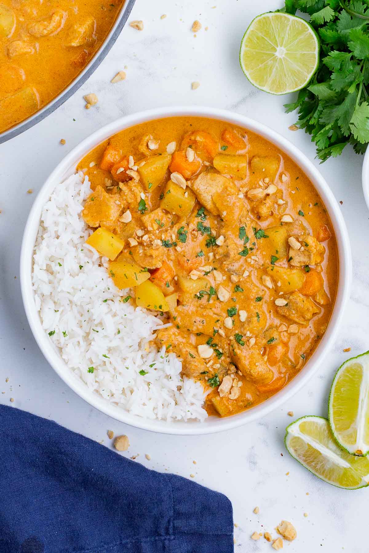 Massaman curry is is served with basmati rice in a white bowl.