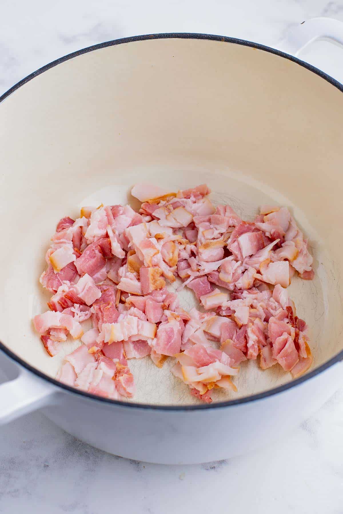 Bacon is cooked in a Dutch oven.