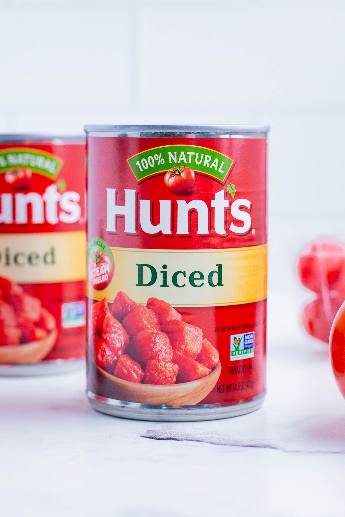 Hunt's canned diced tomatoes with fresh tomatoes nearby.
