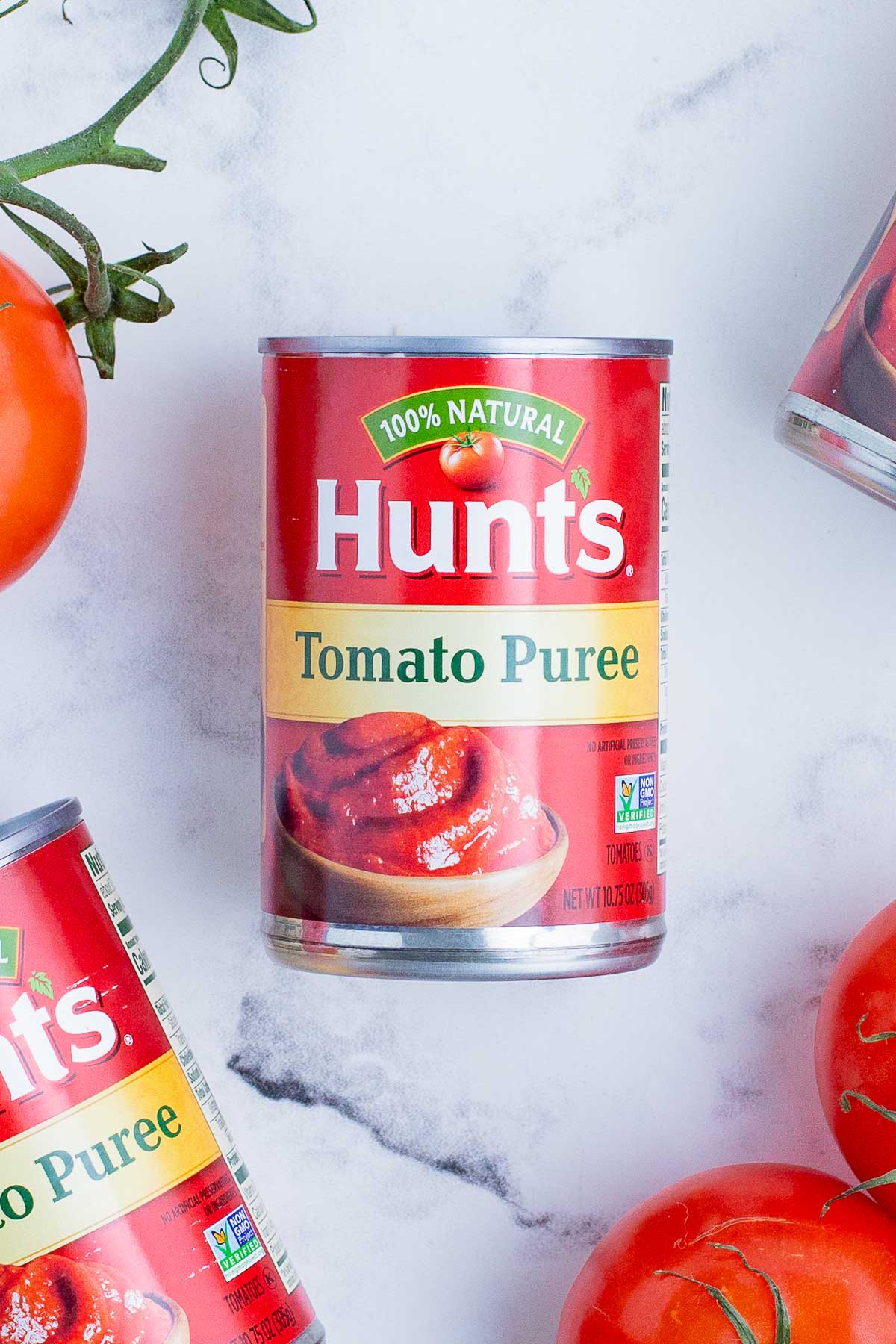 Hunt's tomato puree with fresh tomatoes nearby.