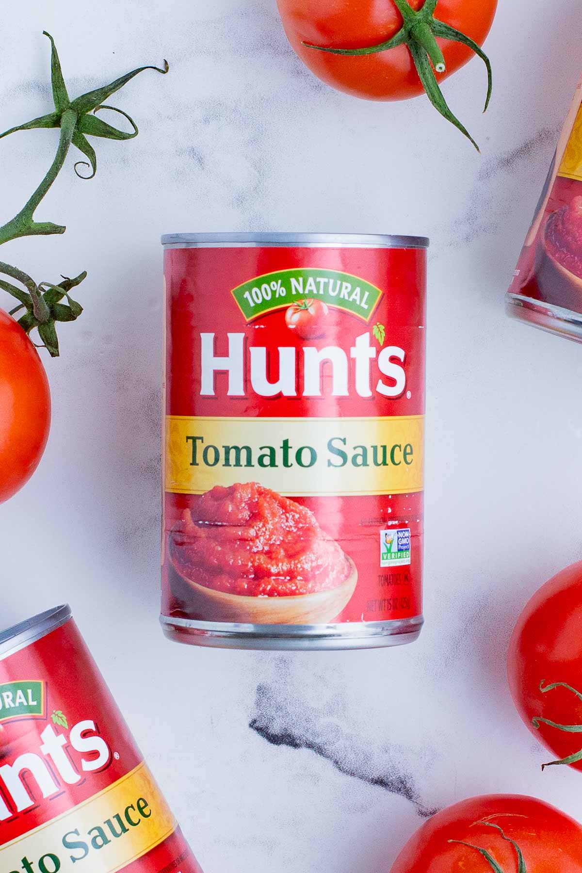 Hunt's canned tomato sauce with fresh tomatoes nearby.