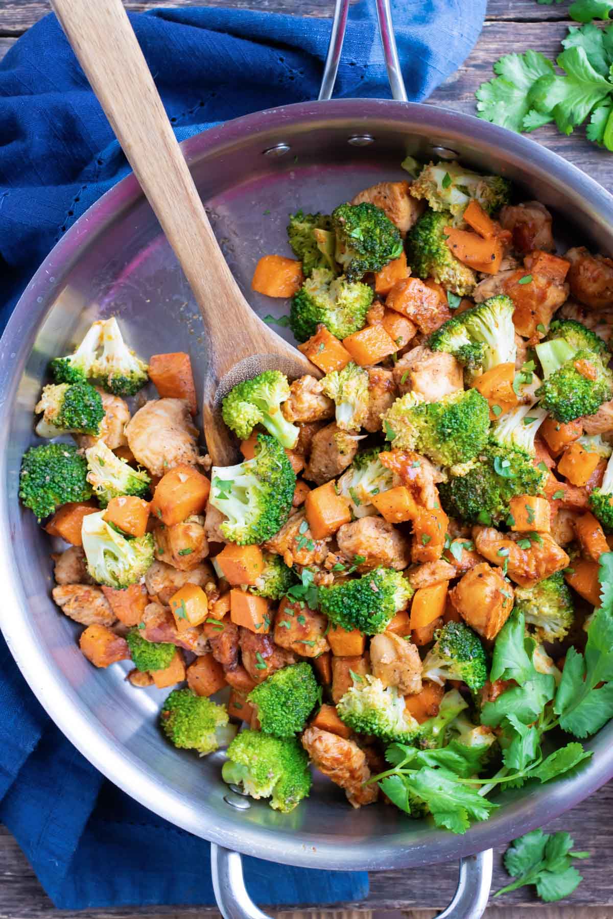 A large skillet with sweet potatoes, broccoli, and chicken covered in a honey barbecue sauce.