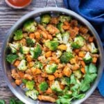 A large skillet full of honey BBQ chicken, sweet potatoes, and broccoli for a one-pot meal.