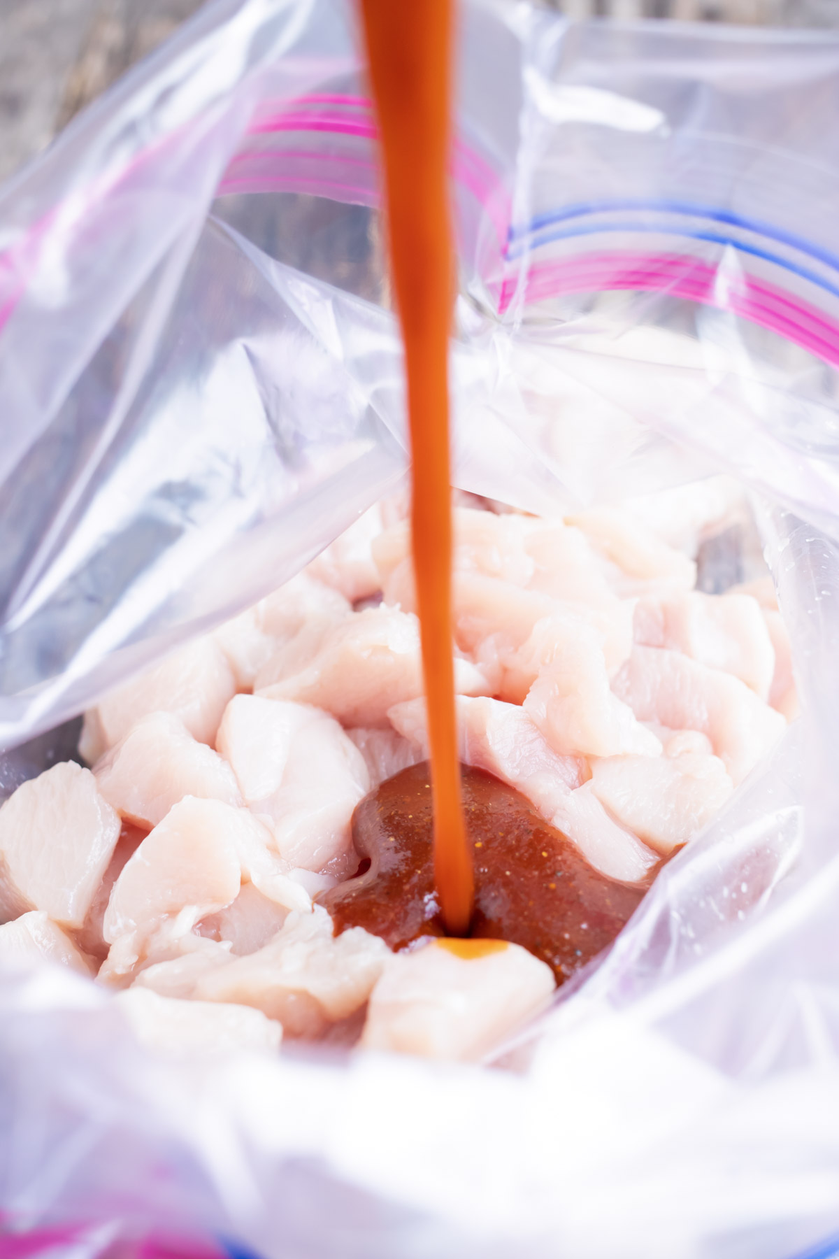 Chicken and marinade are added to a ziploc bag.