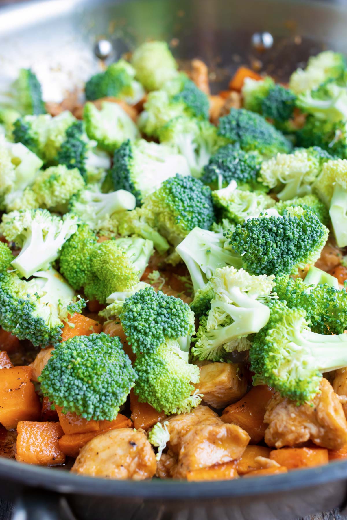 Broccoli is set on top of chicken and sweet potatoes.