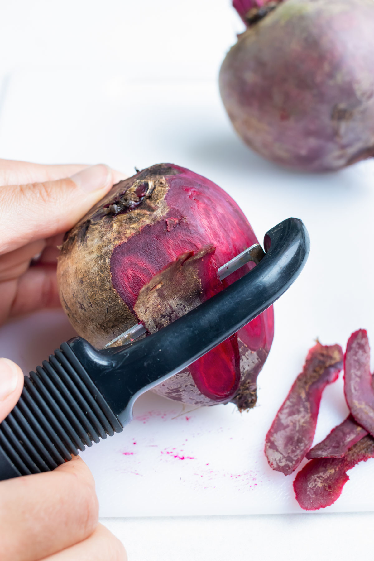 Whole beets are peeled with a vegetable peeler before being roasted.