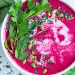 A creamy, vegan, and whole30 beet soup with pumpkin seeds in a white bowl.