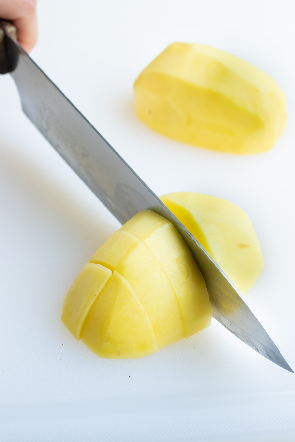 Peeled potatoes are chopped into cubes before cooking.