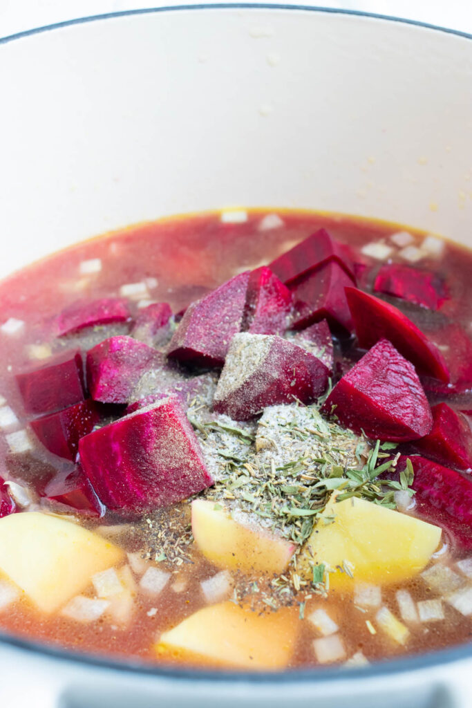 Add chopped beets, potatoes, broth, and herbs to the pot.