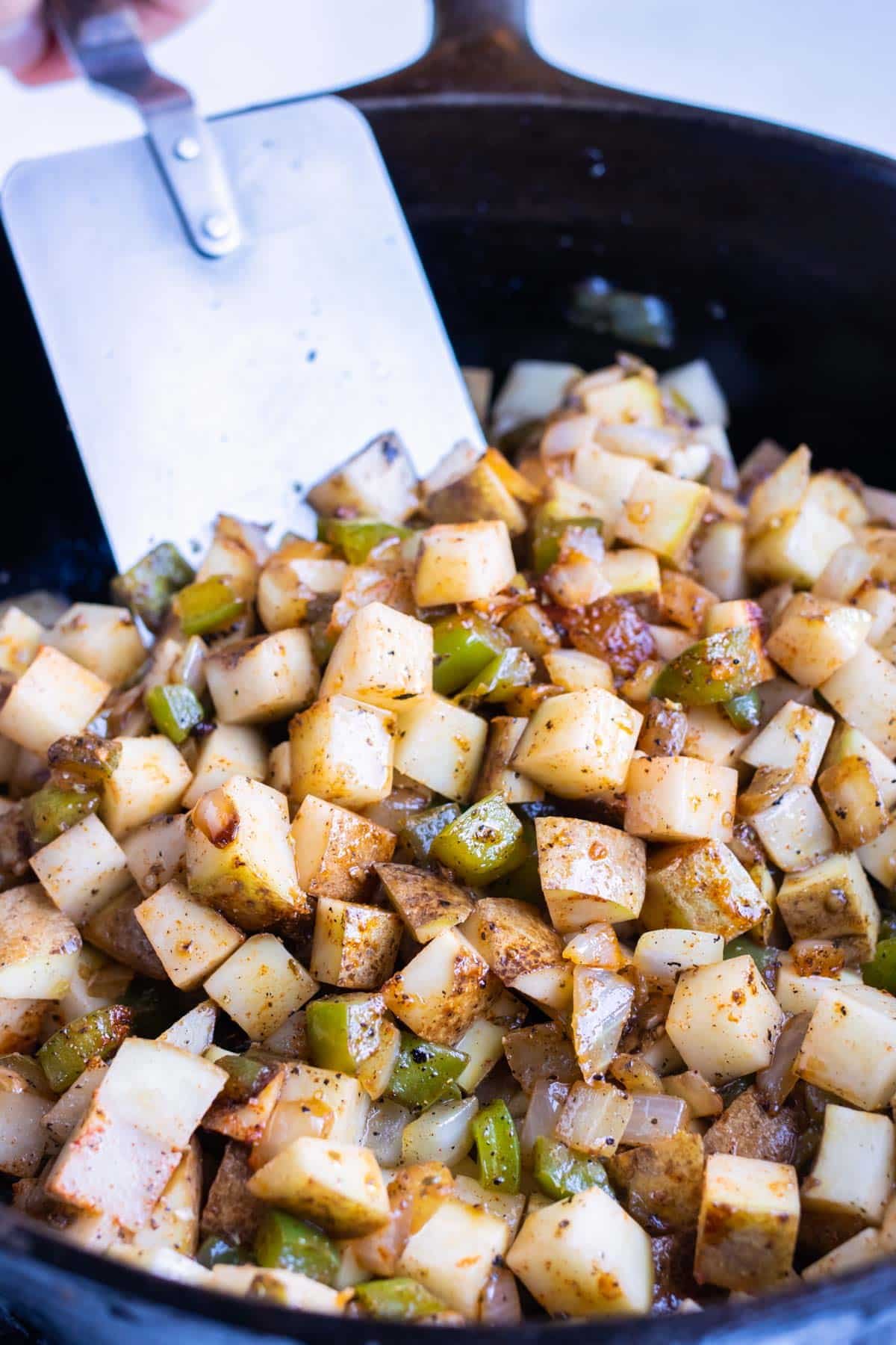 Potatoes and veggies are cooked in the skillet together.