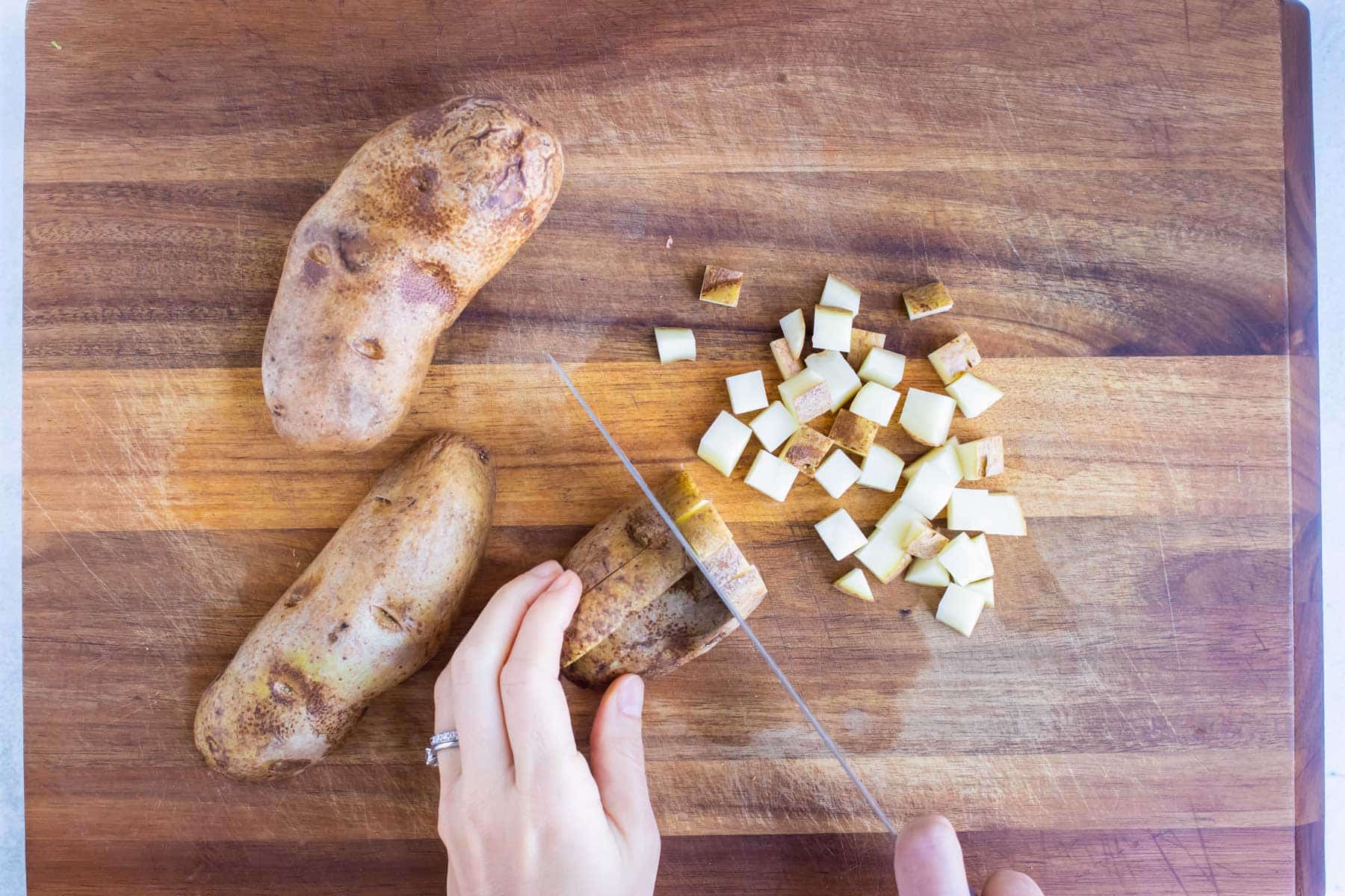 Potatoes are diced on a cutting board for this breakfast recipe.