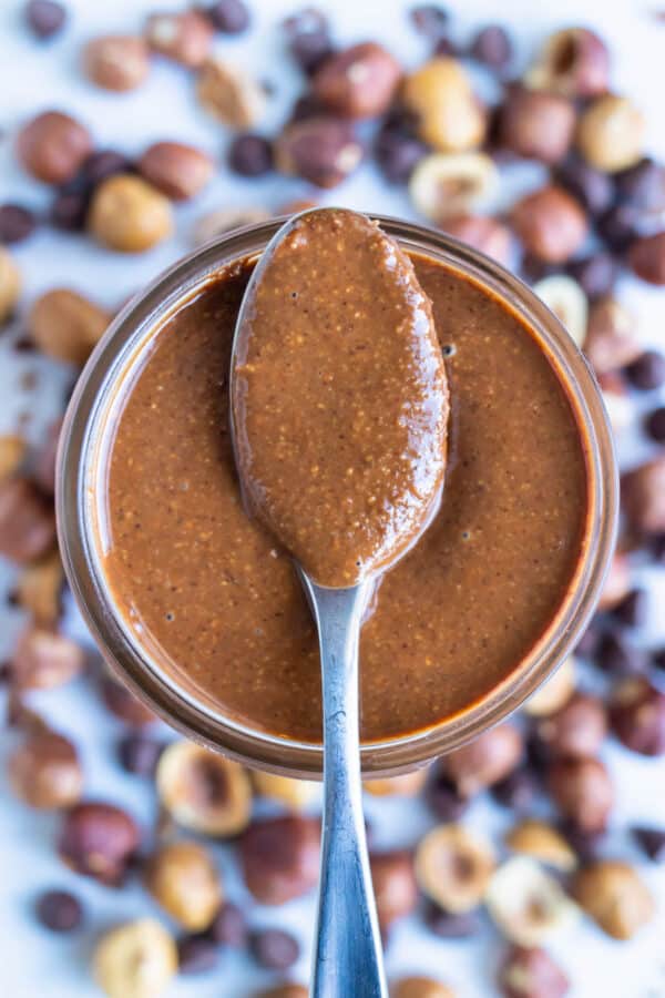 Vegan nutella is shown in a mason jar with a spoon.