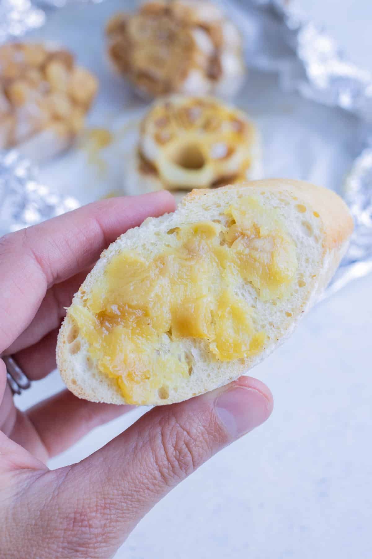 Roasted garlic is spread on top of a piece of bread.