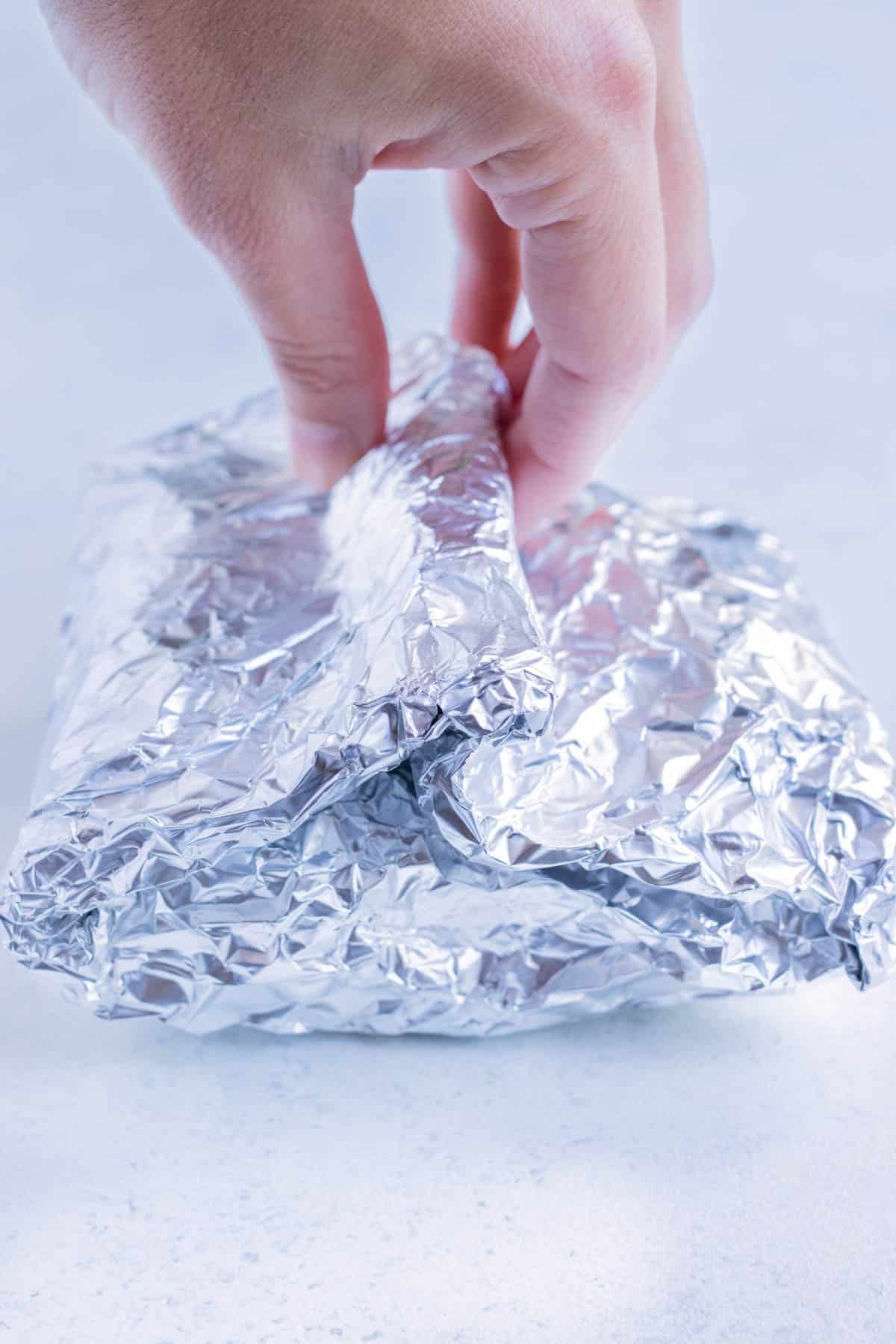 The garlic heads are wrapped inside foil.