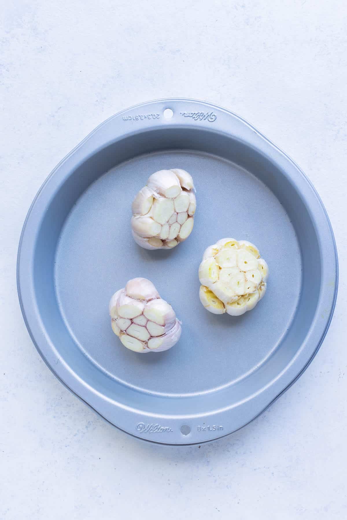 The prepared heads of garlic are placed inside a tin before covering and roasting.
