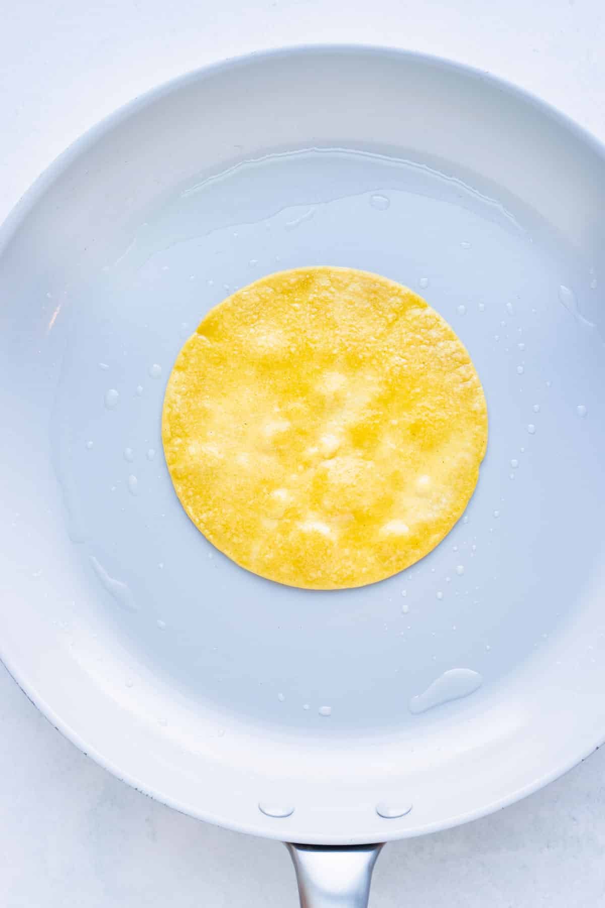 Corn tortillas are cooked on a skillet before being filled.