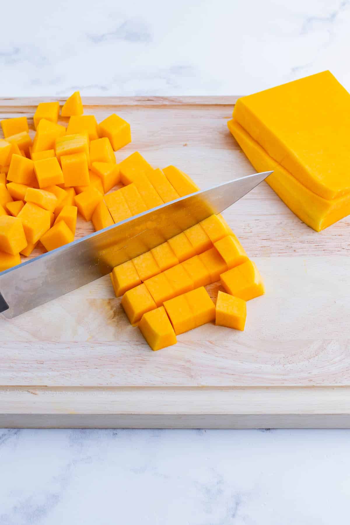 A butternut squash is cut into small cubes.