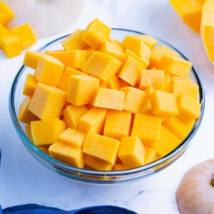 A butternut squash is cut into small cubes.