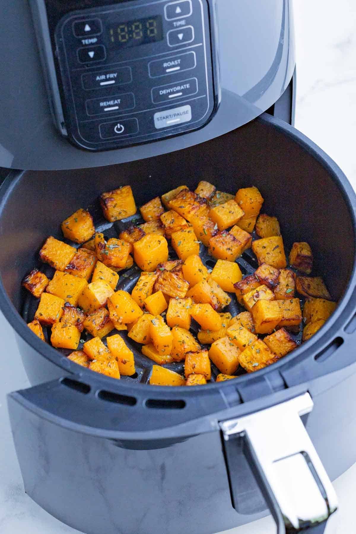 Seasoned butternut squash cubes are cooked in an air fryer.
