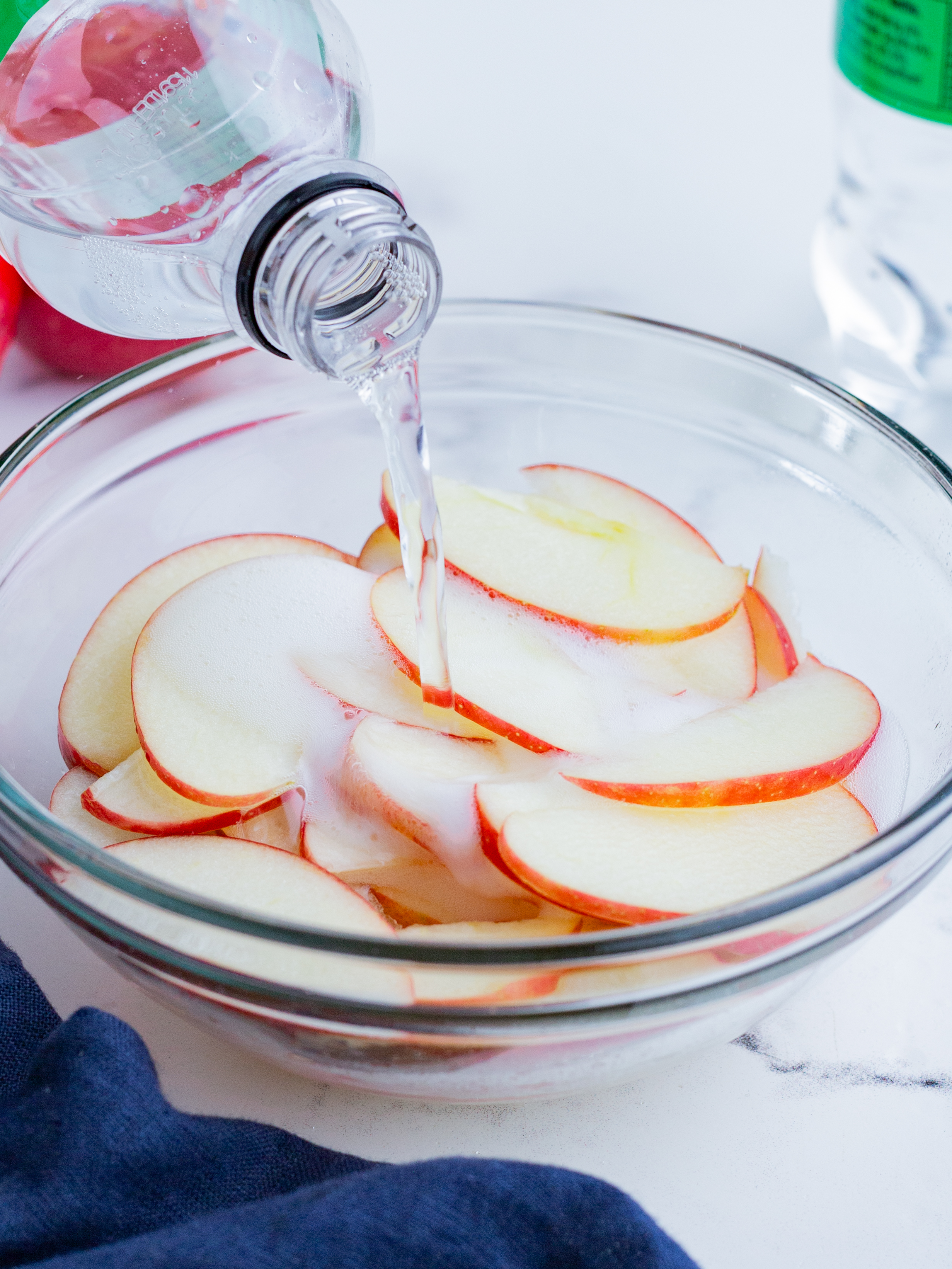 Lemon lime soda being poured over a bowl of sliced apples.