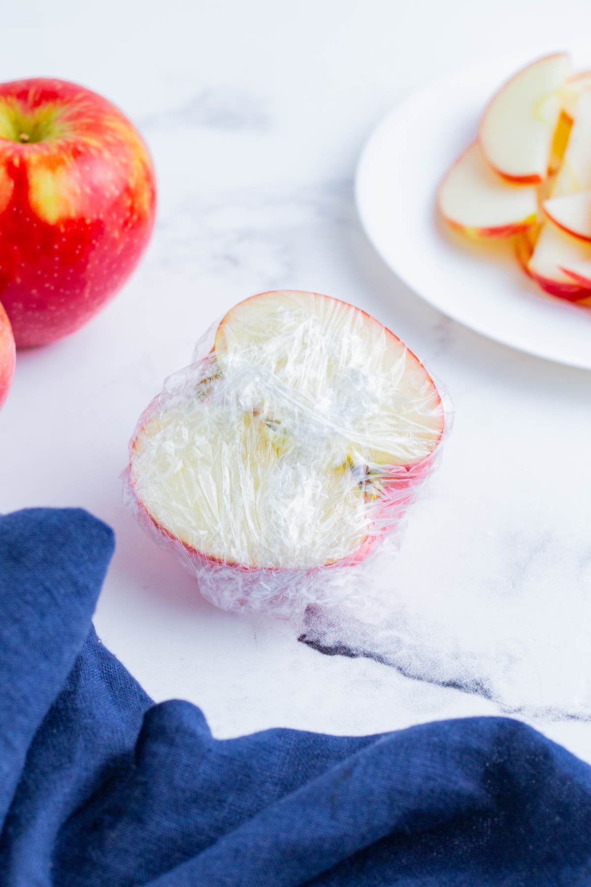 An apple half covered in plastic wrap.