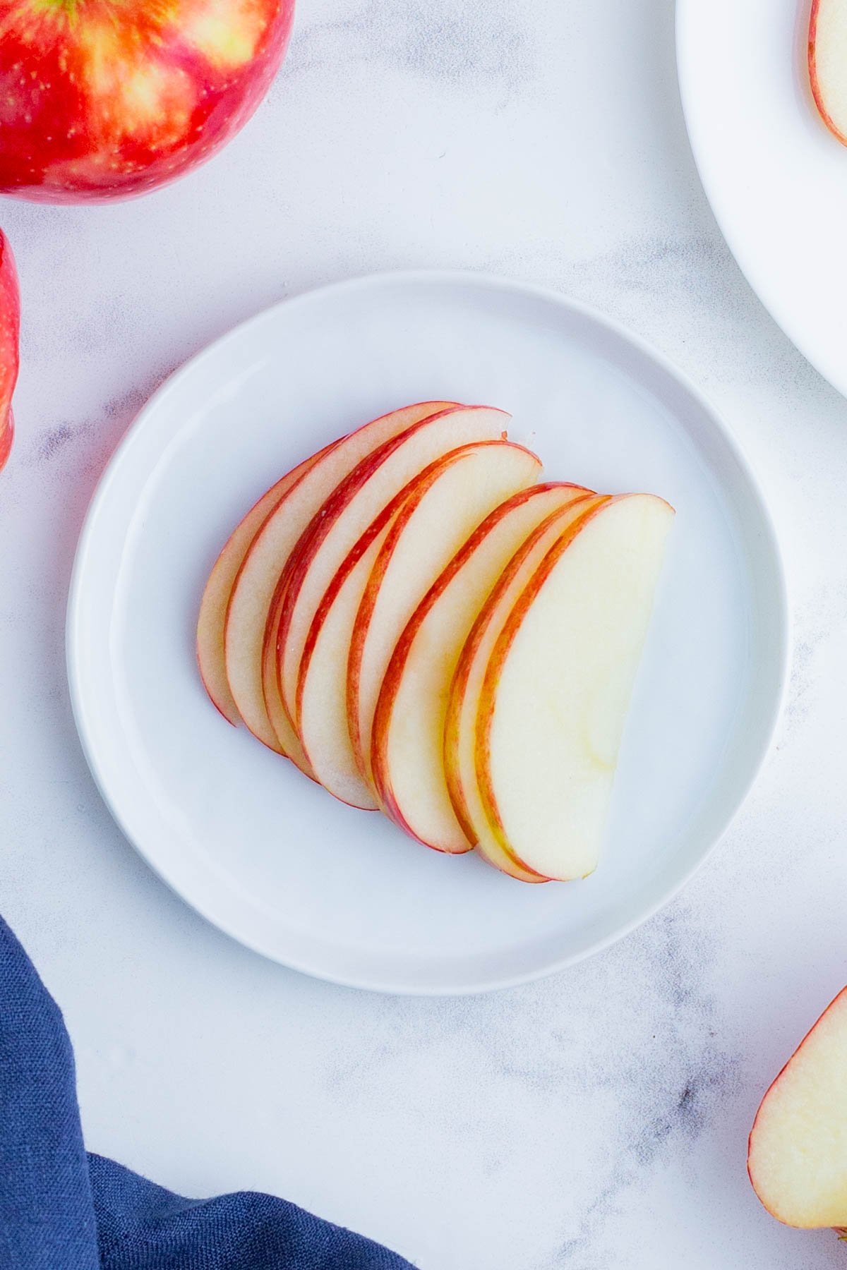 A white plate full of thinly sliced apples.