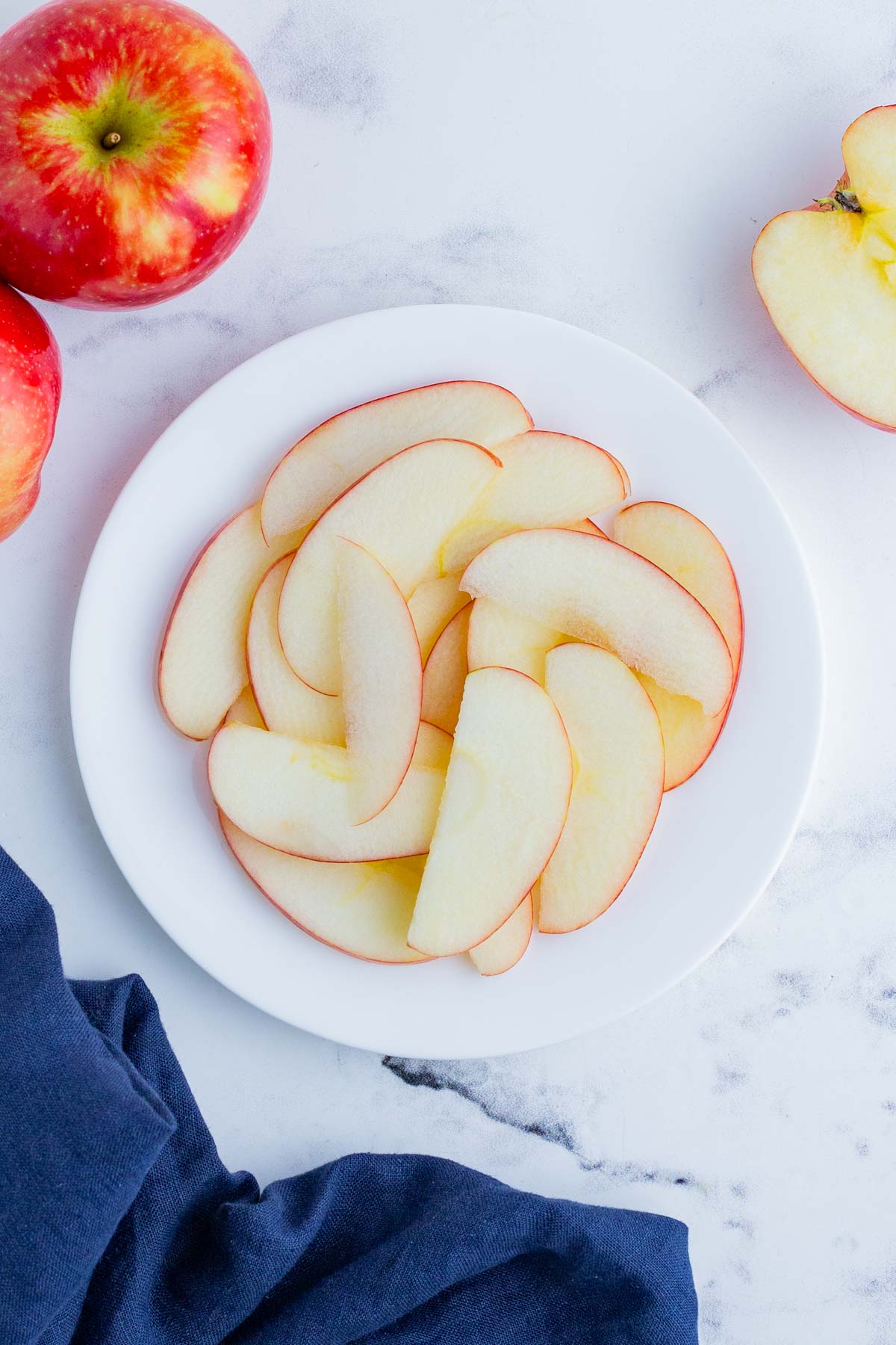 A white plate full of thinly sliced apples.