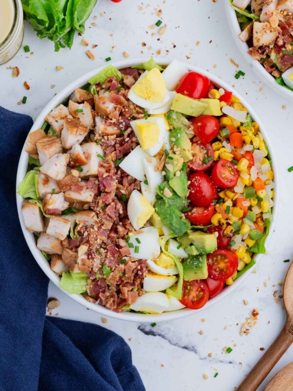An overhead shot of a Cobb salad in a white bowl, with all the essential ingredients plus BBQ chicken.