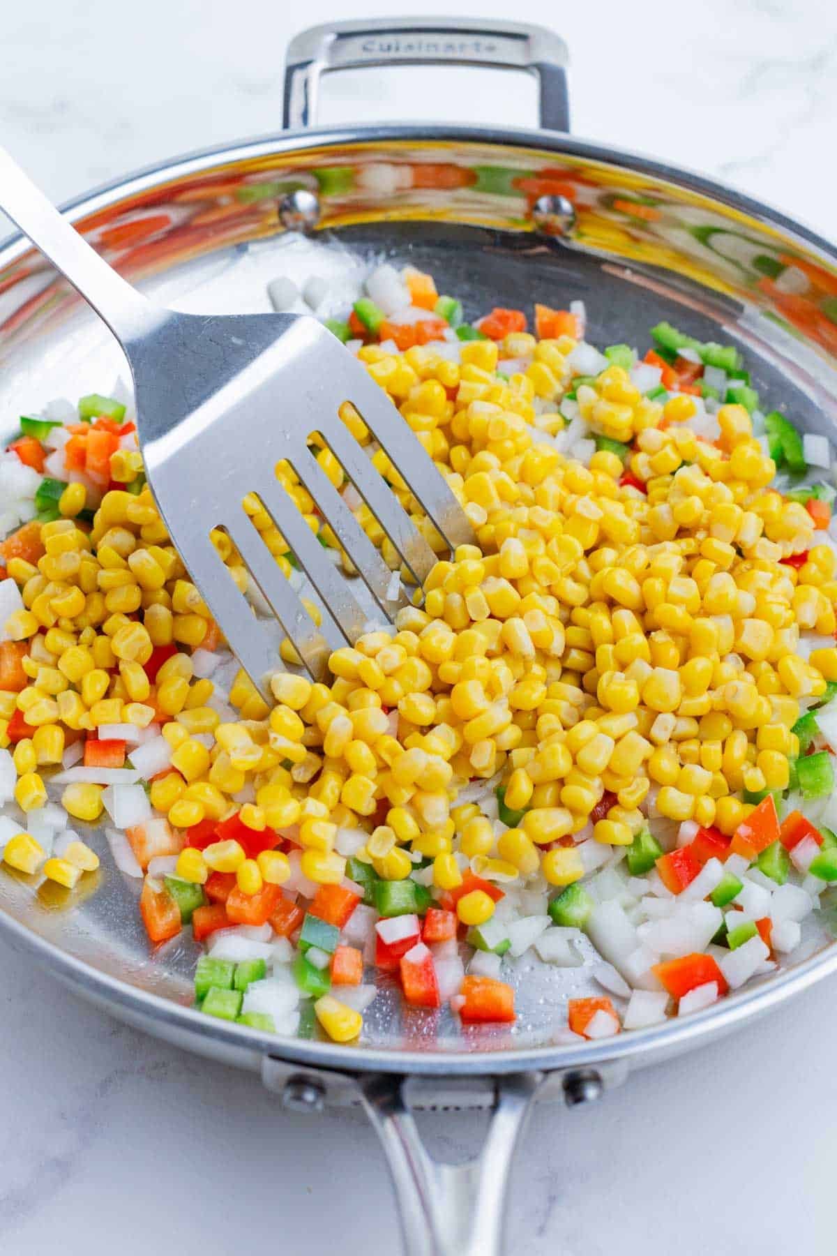 The corn is added to the sauteed veggies.