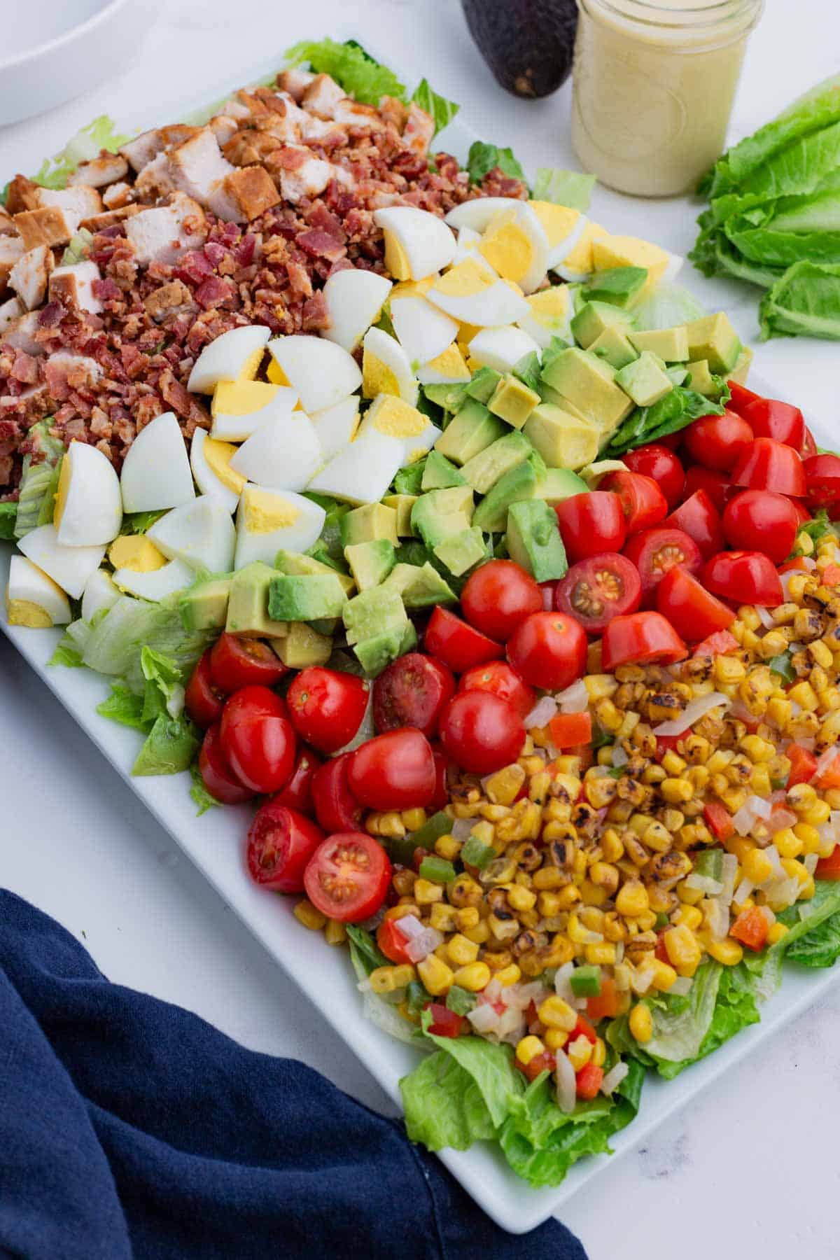 A large platter is loaded with a BBQ Chicken Cobb salad to serve at a party.