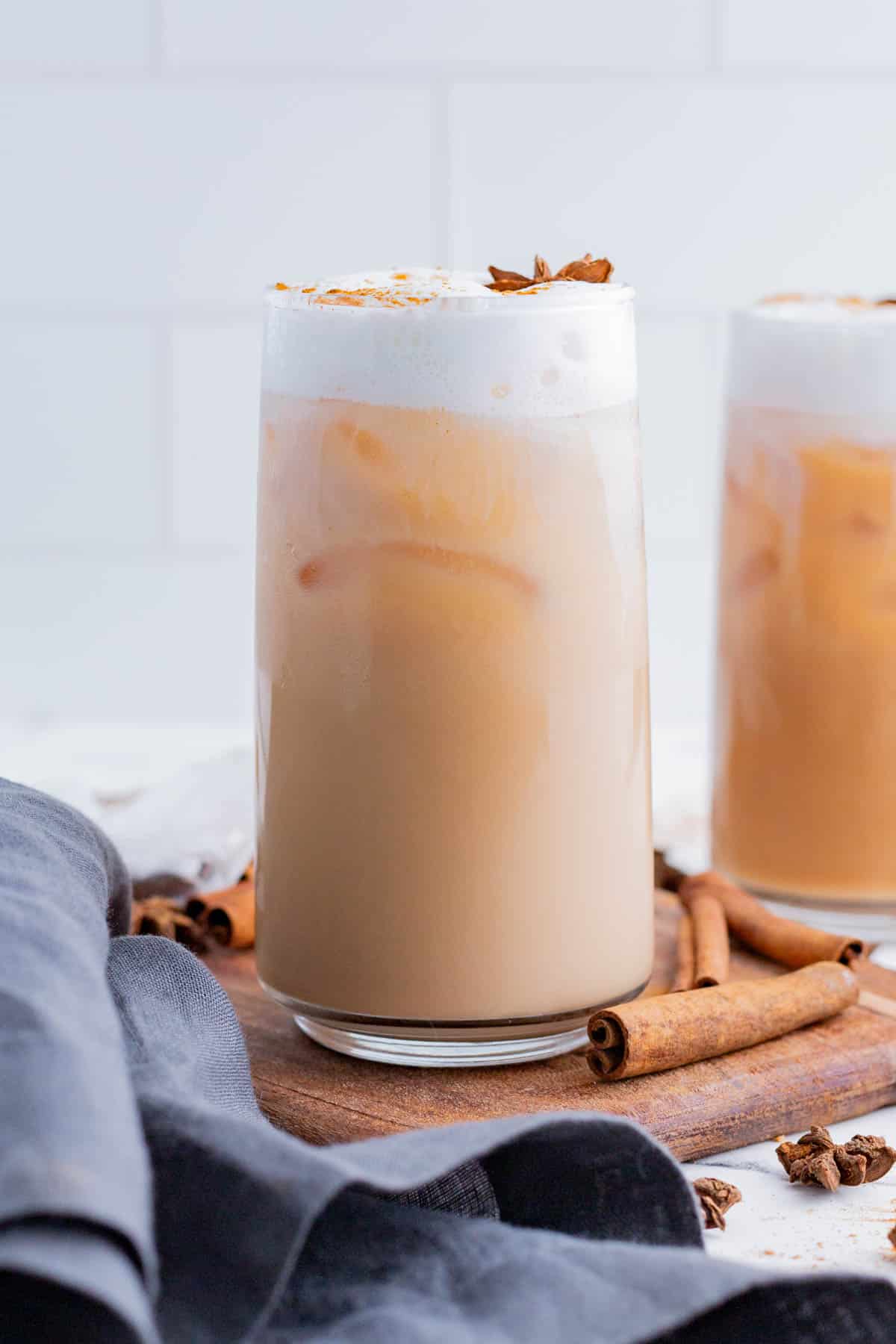 Two glasses of iced chai tea are served with warm spices.
