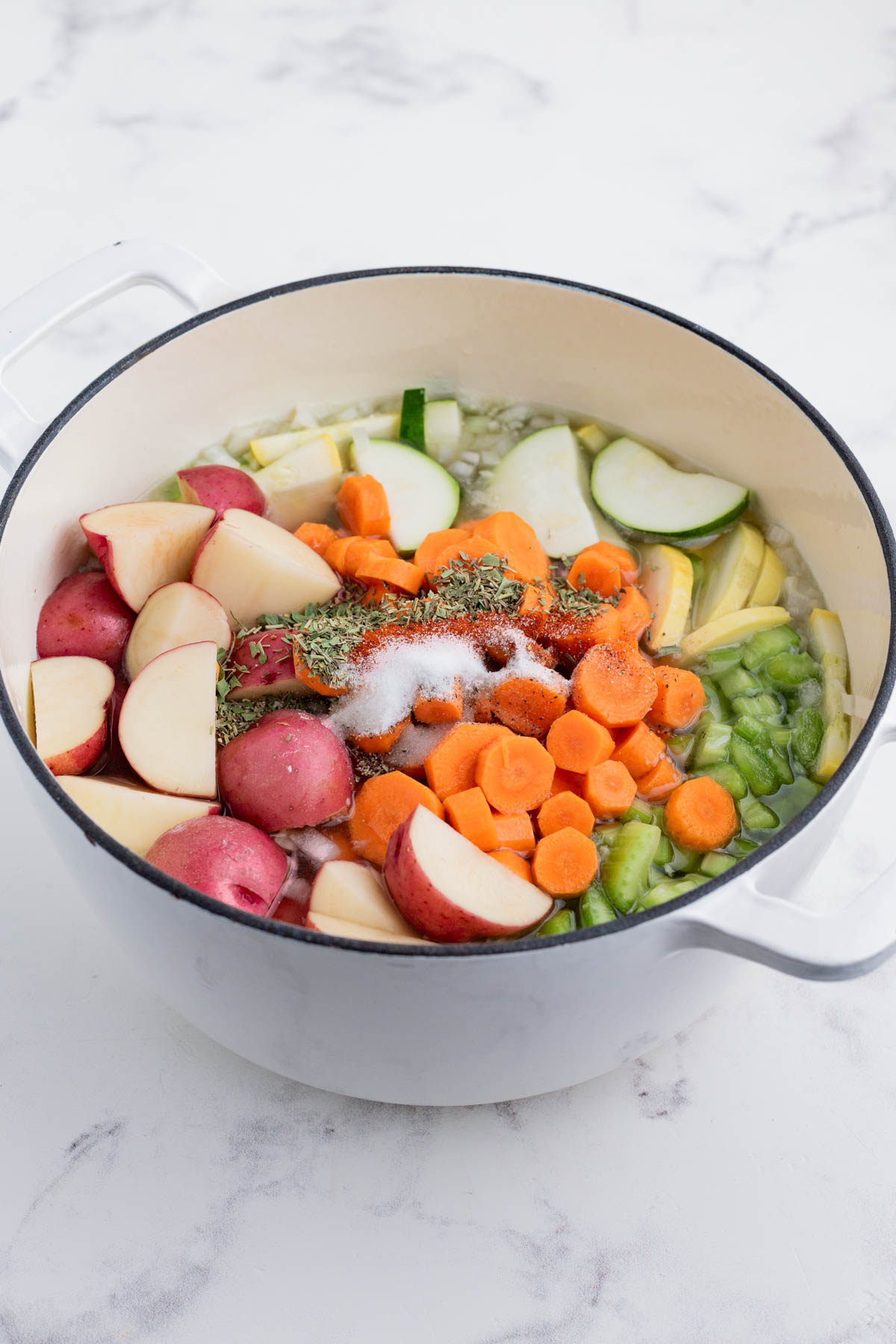 The veggies are added to the pot with broth and onions.