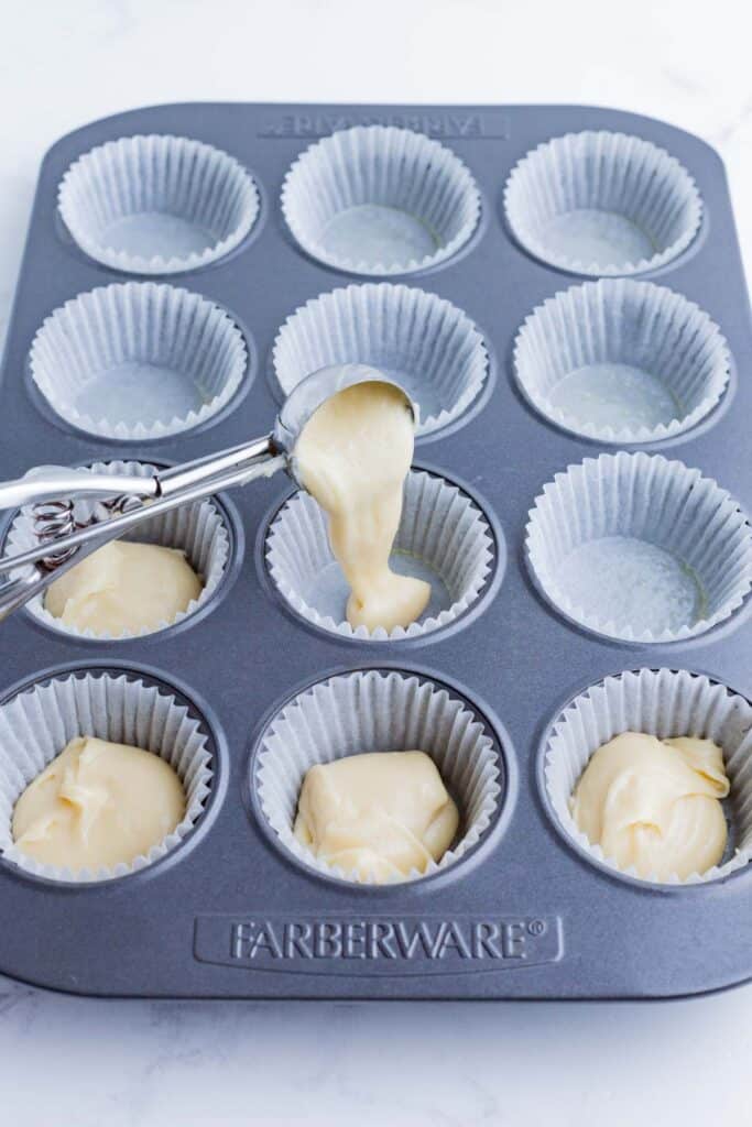 A little bit of batter is added to each muffin cavity.