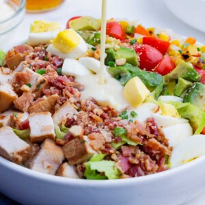 Creamy cobb salad dressing is drizzled over a salad.