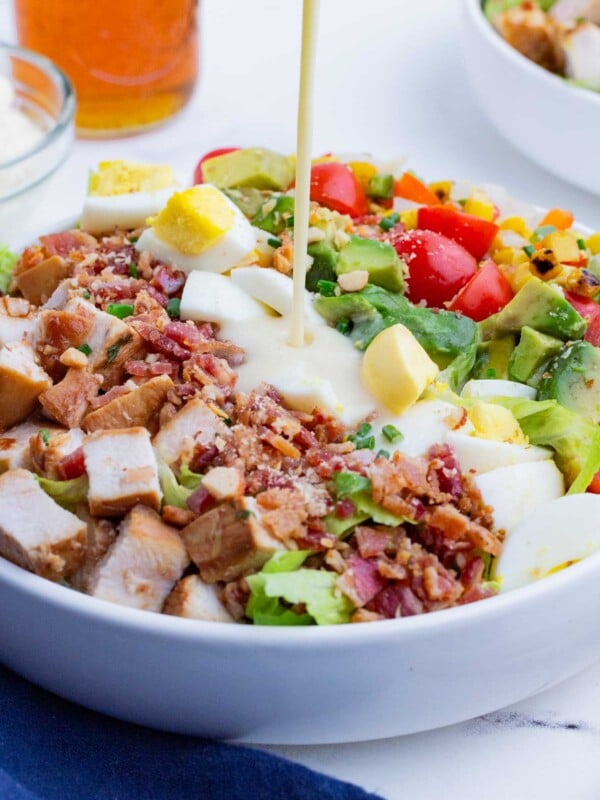 Creamy cobb salad dressing is drizzled over a salad.