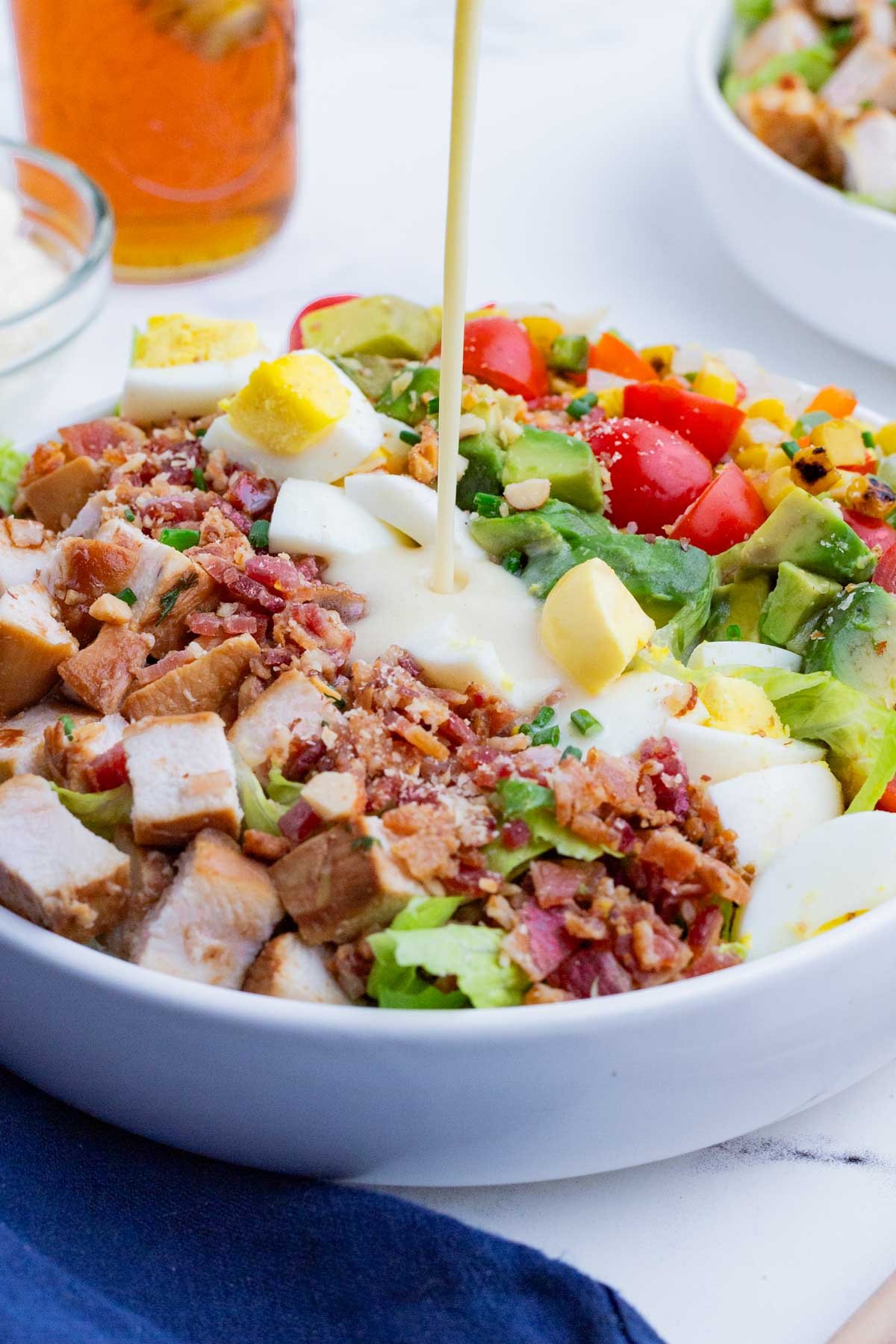 Creamy cobb salad dressing is drizzled over a salad.
