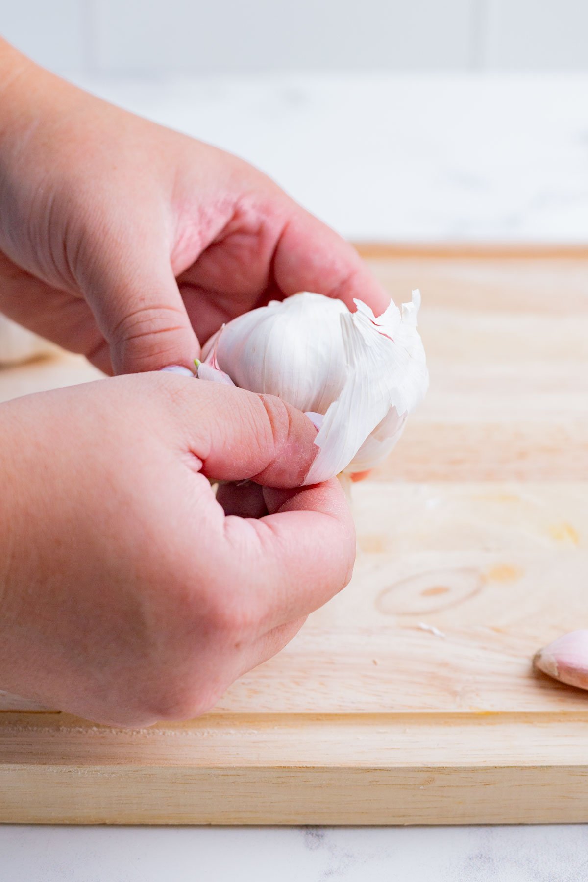 Peeling off the garlic papery skin of a garlic head/bulb.