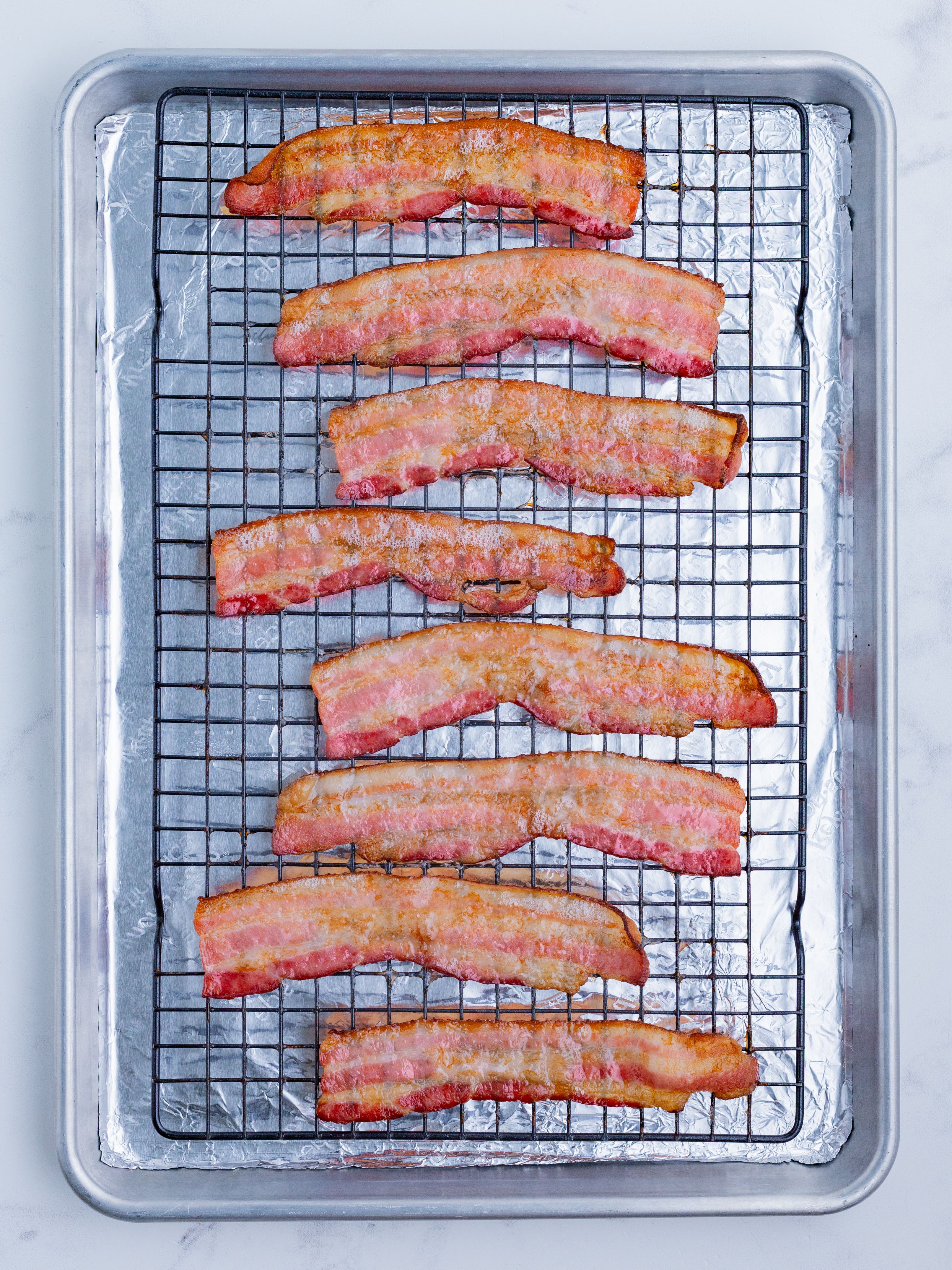 Bacon is cooked on a baking sheet with a wire rack to turn out crispy.